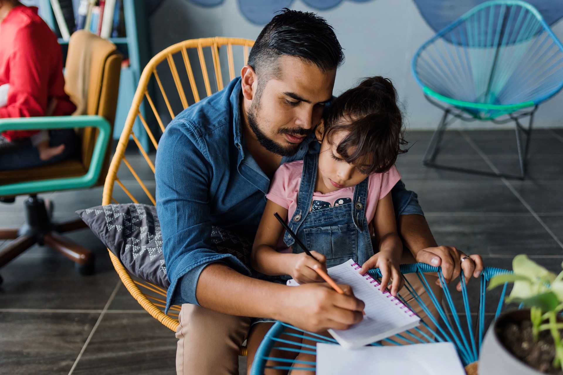 latin father with child daughter doing homework or drawing and painting at home in Mexico Latin America, hispanic family