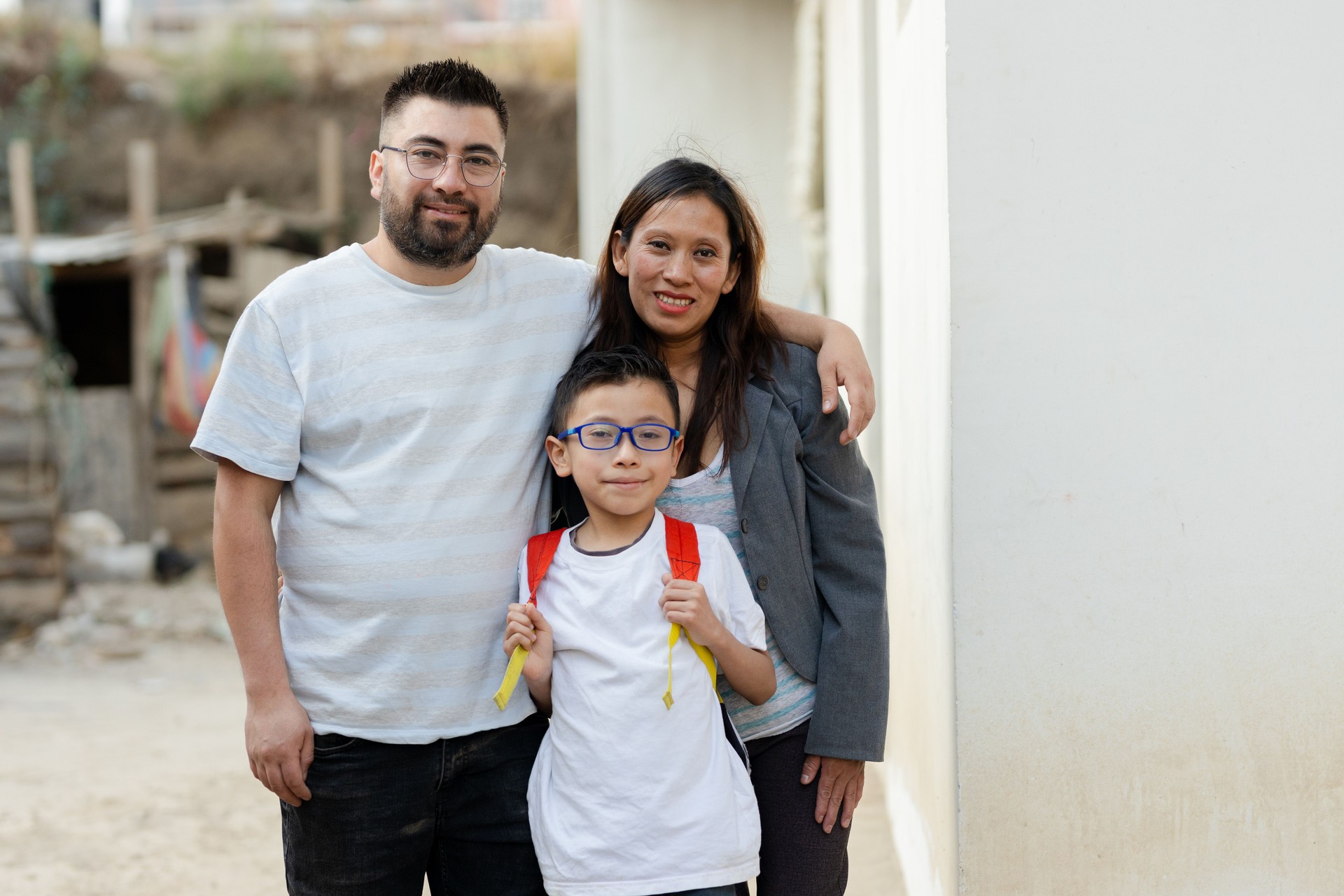 Portrait of Hispanic family - Latino parents with their son who goes to school with his backpack - parents proud of their son who is going to study